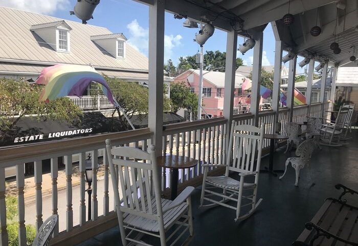 New Orleans house: Gay-friendly hotel porch with rocking chairs and rainbow flags. A welcoming spot for LGBTQ+ travelers.