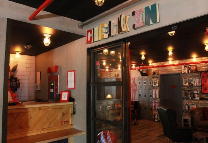 Hotel Gaythering, a gay-friendly hotel. Check-in area with a rustic wood desk, exposed brick, and quirky decor. All adults welcome.