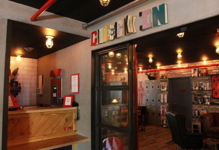 Hotel Gaythering, a gay-friendly hotel. Check-in area with a rustic wood desk, exposed brick, and quirky decor. All adults welcome.