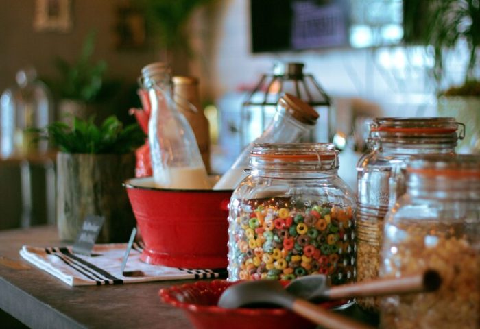 Breakfast bar at the Gaythering, a gay-friendly hotel. Jars of cereal, milk, and granola on display. Crates add rustic charm.