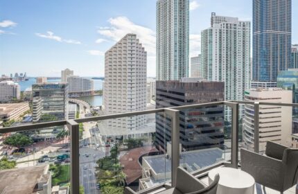 EAST Miami gay-friendly hotel balcony view. High-rise buildings, city streets, and Biscayne Bay are visible. Modern design, perfect for gay travelers.