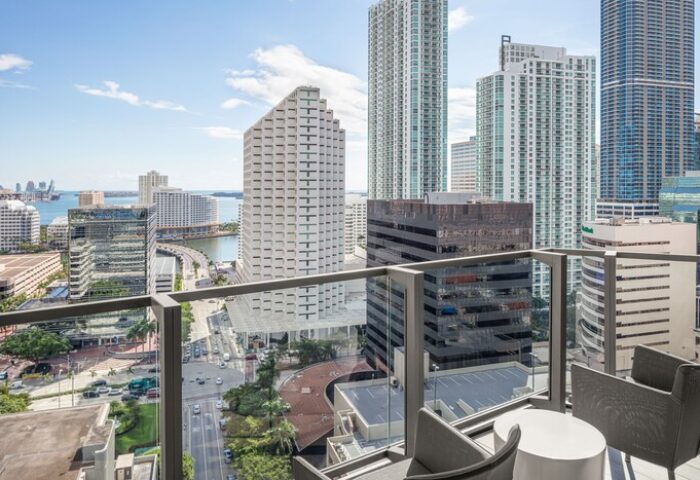 EAST Miami gay-friendly hotel balcony view. High-rise buildings, city streets, and Biscayne Bay are visible. Modern design, perfect for gay travelers.