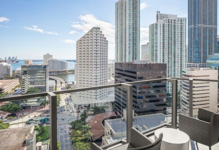 EAST Miami gay-friendly hotel balcony view. High-rise buildings, city streets, and Biscayne Bay are visible. Modern design, perfect for gay travelers.