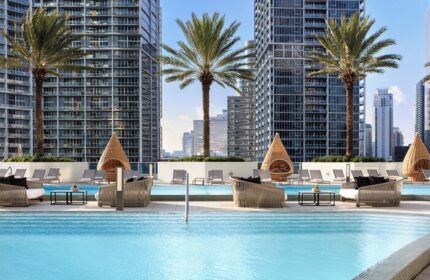 Kimpton EPIC Hotel pool with lounge chairs, palm trees, and city views. A gay-friendly hotel for gay men travel in Miami, Florida.