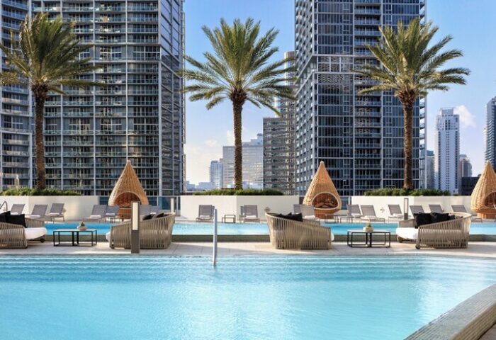 Kimpton EPIC Hotel pool with lounge chairs, palm trees, and city views. A gay-friendly hotel for gay men travel in Miami, Florida.