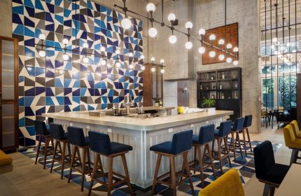 Hotel Indigo Miami Brickell bar area. Gay-friendly hotel with stylish blue & gray geometric wall tiles and blue bar stools. Modern design.