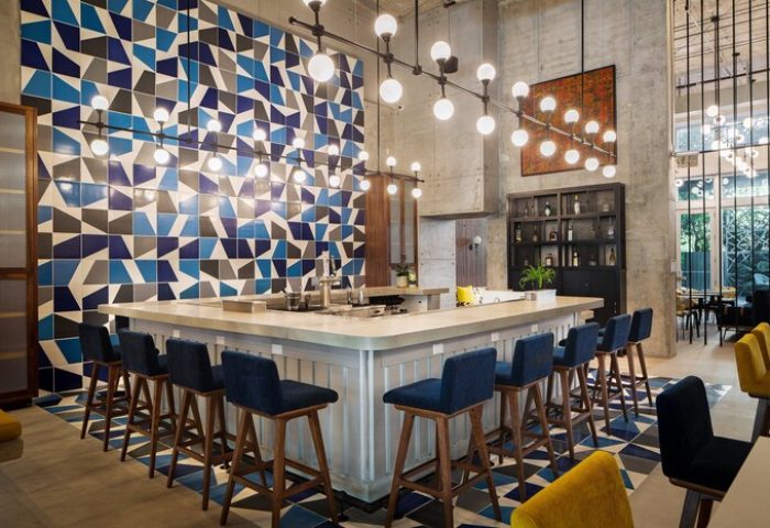 Hotel Indigo Miami Brickell bar area. Gay-friendly hotel with stylish blue & gray geometric wall tiles and blue bar stools. Modern design.