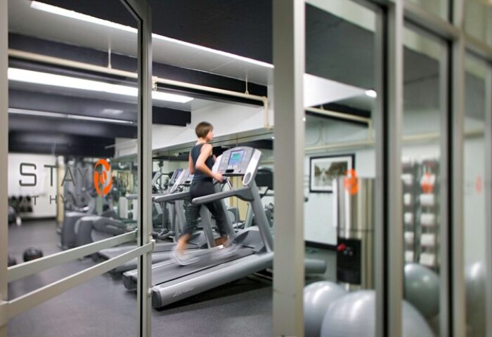 Hyatt Regency Miami gay-friendly hotel gym. Woman using a treadmill. Fitness center with equipment for a healthy lifestyle.