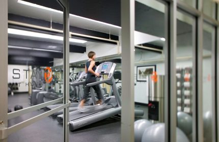 Hyatt Regency Miami gay-friendly hotel gym. Woman using a treadmill. Fitness center with equipment for a healthy lifestyle.