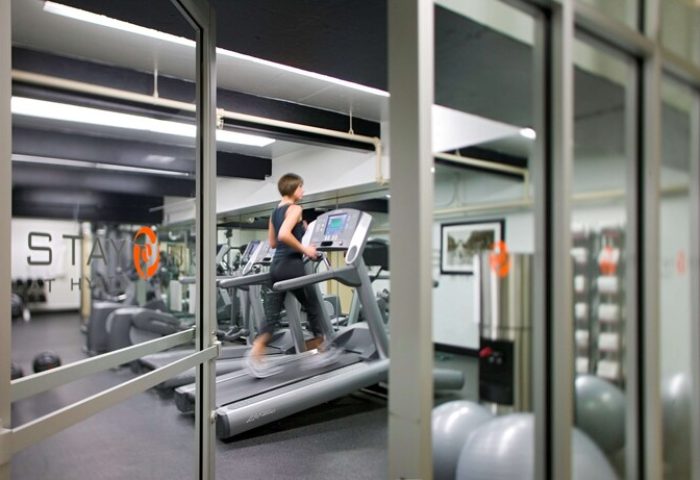 Hyatt Regency Miami gay-friendly hotel gym. Woman using a treadmill. Fitness center with equipment for a healthy lifestyle.
