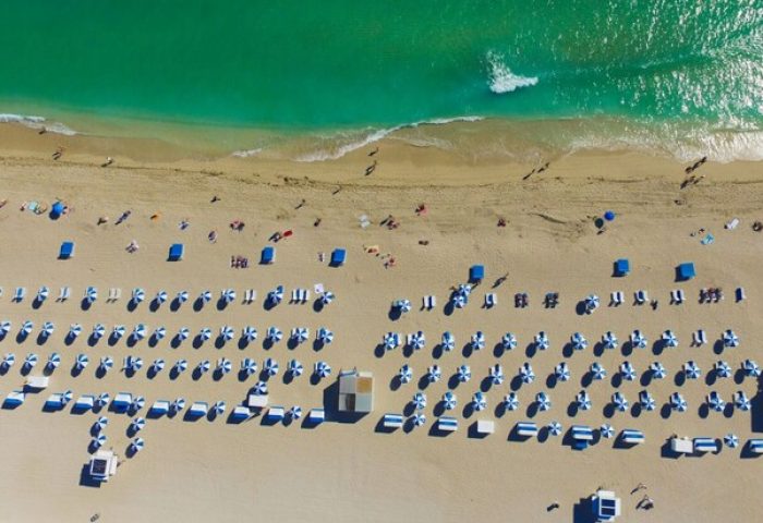 Dream South Beach, a gay-friendly hotel. Aerial view of the beach with turquoise water, sand, umbrellas, and chairs. Perfect for gay travel.
