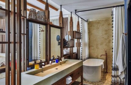 25hours Hotel One Central bathroom. Gay-friendly hotel with double sink, bathtub, wooden accents, mirrors, and stylish decor. Luxury travel.