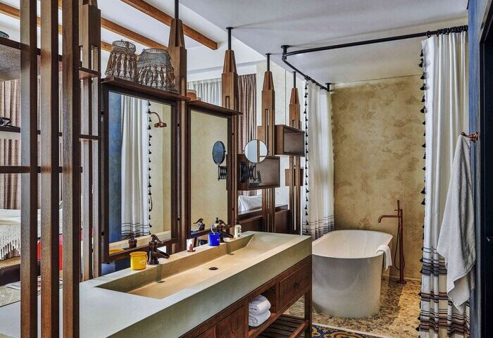 25hours Hotel One Central bathroom. Gay-friendly hotel with double sink, bathtub, wooden accents, mirrors, and stylish decor. Luxury travel.
