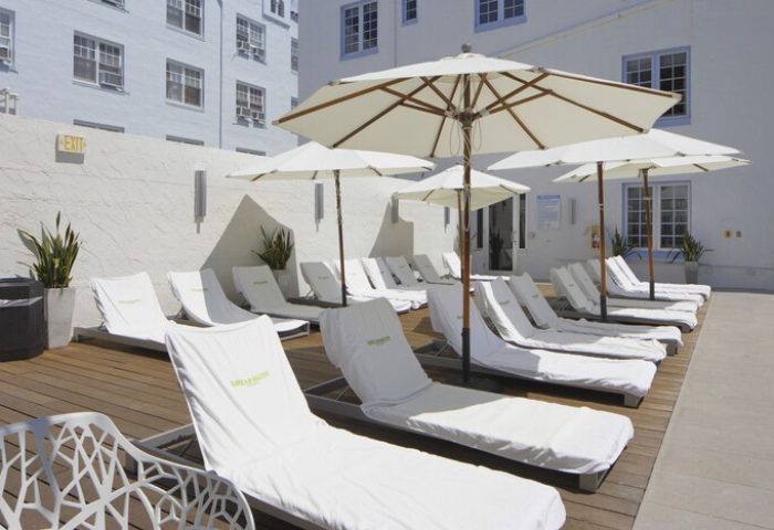 Hotel Breakwater South Beach's pool area. Lounge chairs with white covers and umbrellas. A gay-friendly hotel in South Beach.