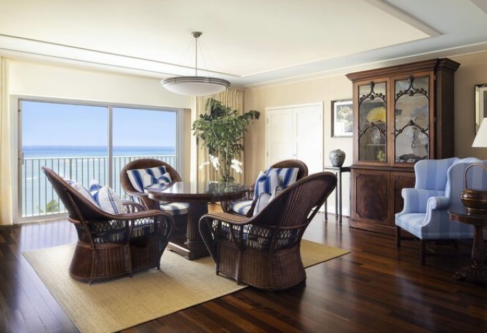 Kahala Hotel and Resort gay-friendly suite. Ocean view, wicker chairs, and blue accents create a luxurious, welcoming space for LGBTQ+ travelers.
