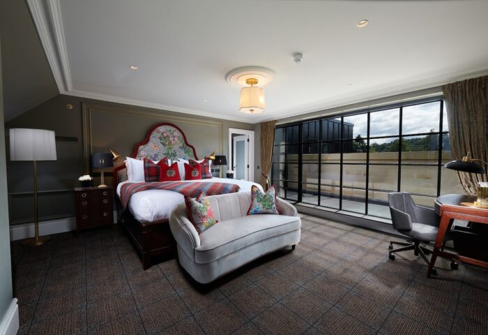 Cameron House on Loch Lomond gay-friendly hotel room. Bedroom with large bed, sofa, desk, and expansive window. Luxury gay travel.