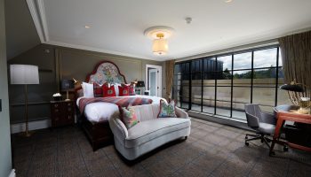 Cameron House on Loch Lomond gay-friendly hotel room. Bedroom with large bed, sofa, desk, and expansive window. Luxury gay travel.