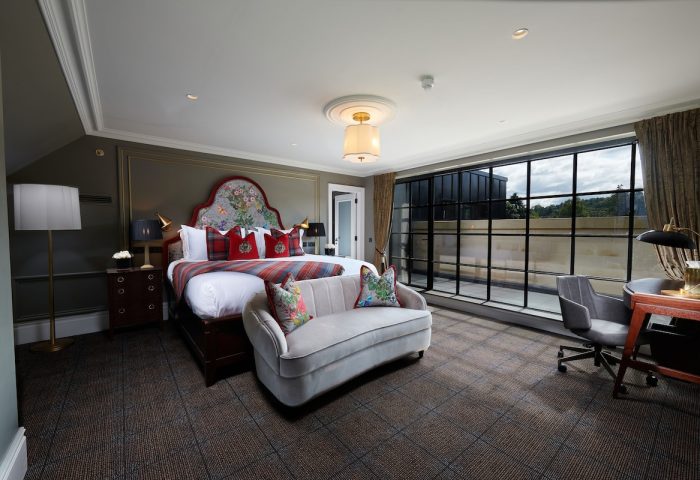 Cameron House on Loch Lomond gay-friendly hotel room. Bedroom with large bed, sofa, desk, and expansive window. Luxury gay travel.