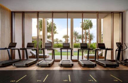 Atlantis The Royal gay-friendly hotel gym. Treadmills face a window with palm trees. A luxury fitness experience for gay travelers.
