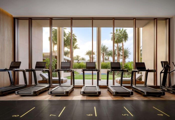 Atlantis The Royal gay-friendly hotel gym. Treadmills face a window with palm trees. A luxury fitness experience for gay travelers.