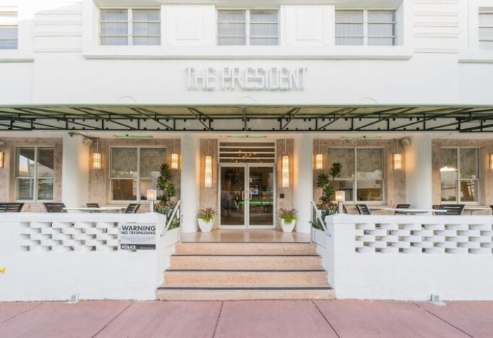 President Hotel, a gay-friendly hotel. Exterior view of the entrance with steps, outdoor seating, and The President sign above the doorway.