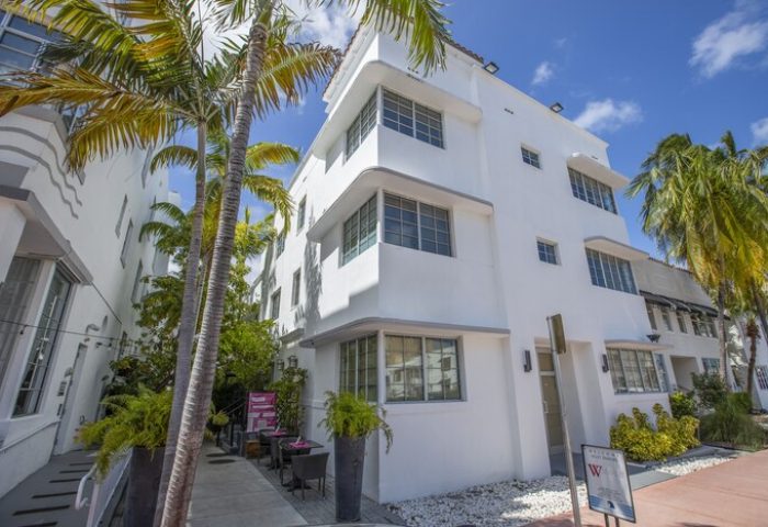 Posh South Beach gay-friendly hotel exterior. White art deco building with palm trees. A stylish choice for gay travelers in South Beach.