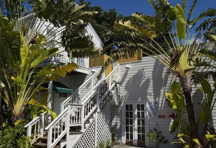 Wicker Guesthouse exterior. Gay-friendly hotel with tropical plants. White building with stairs. A great choice for gay men travelers.