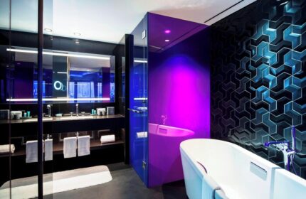 W Dubai - The Palm gay-friendly hotel bathroom. Modern design with a bathtub, vanity, and stylish blue and purple lighting.