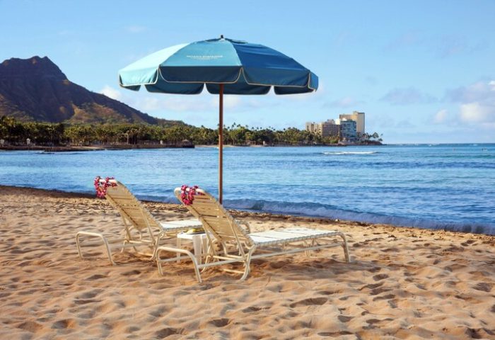 Waikiki Beach chairs under an umbrella, Moana Surfrider, a Westin Resort & Spa in Hawaii. Gay-friendly hotel with ocean view.