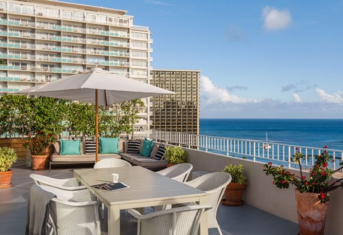 Hilton Vacation Club The Modern Honolulu gay-friendly hotel terrace. Ocean view, table, chairs, and lounge seating. Ideal for gay men travel.