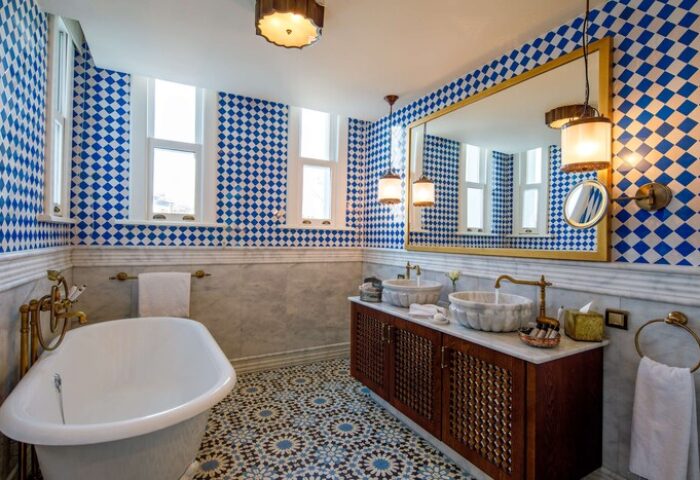 Hagia Sofia Mansions Istanbul bathroom. Luxurious gay-friendly hotel room with blue diamond tiles, marble sinks, and patterned floor. Curio Collection.