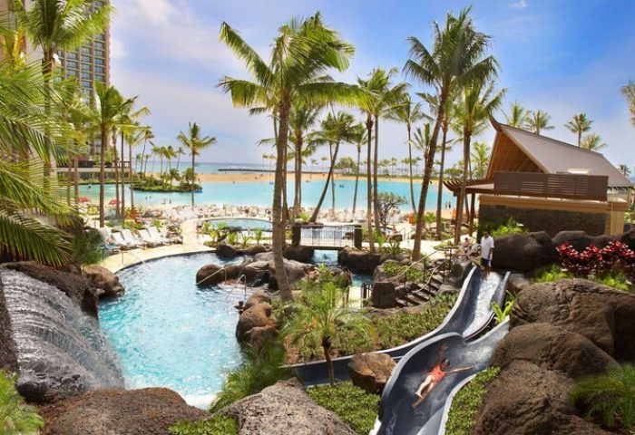 Hilton Hawaiian Village Waikiki Beach Resort pool and waterslide. Gay-friendly hotel with beach access, palm trees, and lagoon views.