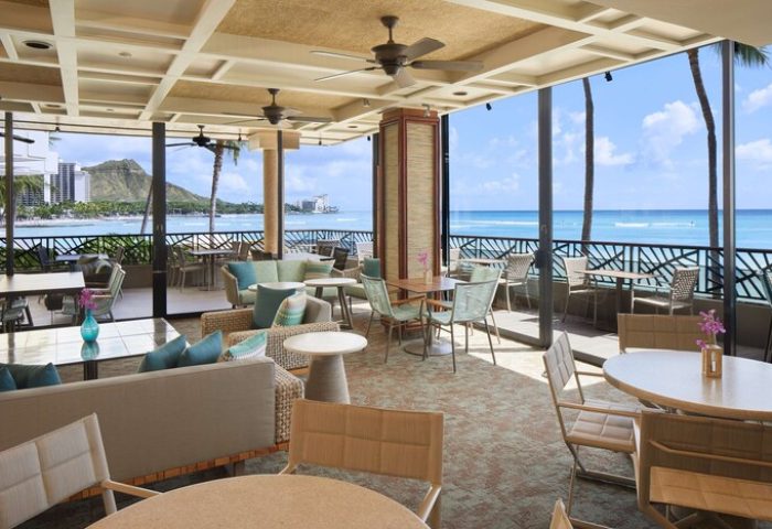 OUTRIGGER Waikiki Beach Resort's oceanfront dining area. Gay-friendly hotel with tables, chairs, and a view of the beach and Diamond Head.