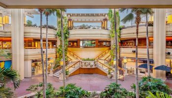 Hyatt Regency Waikiki Beach Resort & Spa interior. Palm trees, stairs, and shops. Gay-friendly hotel in Hawaii for gay men travel.