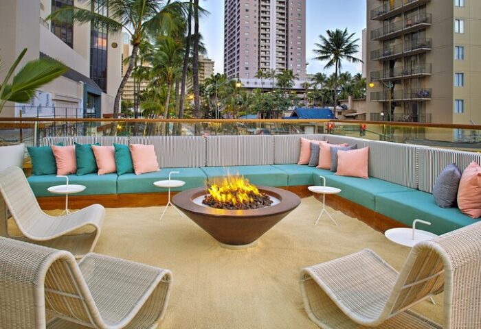 The Laylow Autograph Collection gay-friendly hotel outdoor lounge area with fire pit, seating, and city view. Relaxing travel for gay men in Hawaii.