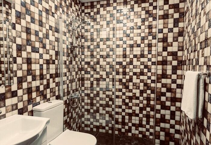 Cheers Midtown Hostel gay-friendly hotel bathroom. Checkered tile shower, toilet, sink, & black marble floor. Perfect for gay travel.