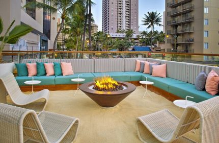 The Laylow Autograph Collection gay-friendly hotel outdoor lounge area with fire pit, seating, and city view. Relaxing travel for gay men in Hawaii.