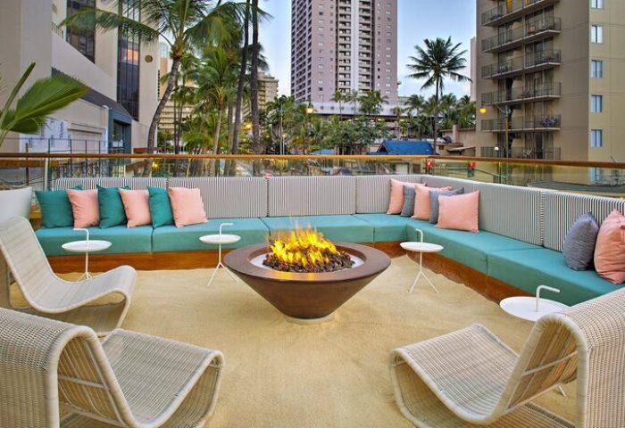 The Laylow Autograph Collection gay-friendly hotel outdoor lounge area with fire pit, seating, and city view. Relaxing travel for gay men in Hawaii.