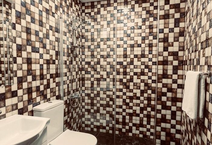 Cheers Midtown Hostel gay-friendly hotel bathroom. Checkered tile shower, toilet, sink, & black marble floor. Perfect for gay travel.