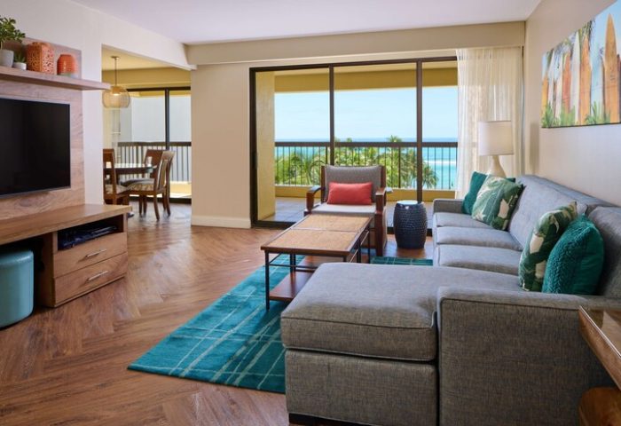 Aston Waikiki Beach Tower suite interior. Living area with ocean view, balcony. Gay-friendly hotel. Modern design, relaxing space.