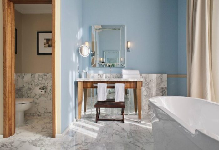 Bathroom in St. Pancras Renaissance Hotel, London. Gay-friendly hotel with bathtub, sink, mirror, marble floor, and separate toilet room.