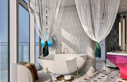 W Dubai - Mina Seyahi gay-friendly hotel bathroom. Modern design with a marble tub, sheer curtains, and colorful accents. Luxury gay travel.