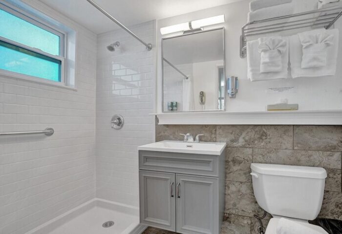 Bathroom at The Grand Resort and Spa, an all-male, gay-friendly hotel. Features shower, sink, mirror, toilet, and towels.