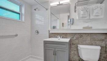 Bathroom at The Grand Resort and Spa, an all-male, gay-friendly hotel. Features shower, sink, mirror, toilet, and towels.
