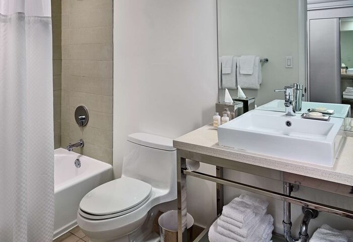 Bathroom at the gay-friendly Sonesta Fort Lauderdale Beach hotel. Features a tub, toilet, sink, mirror, and towels.