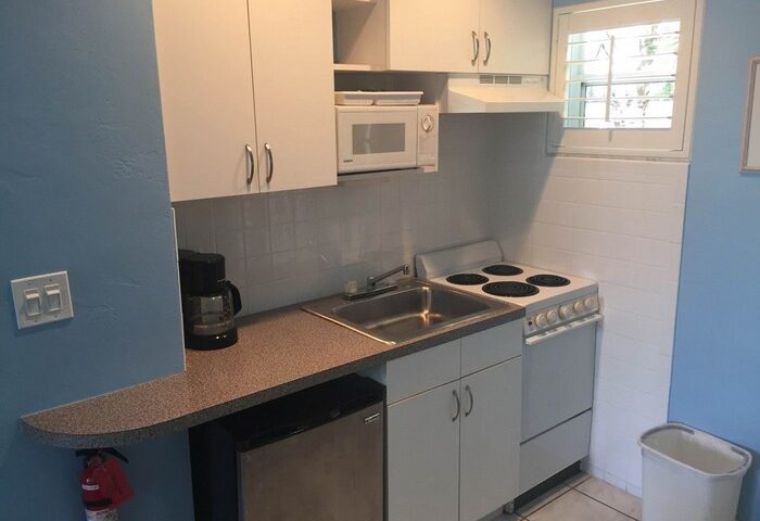 Coral Reef Guesthouse gay-friendly hotel kitchenette. Features include a stove, microwave, sink, mini-fridge, and cabinets for a comfortable stay.