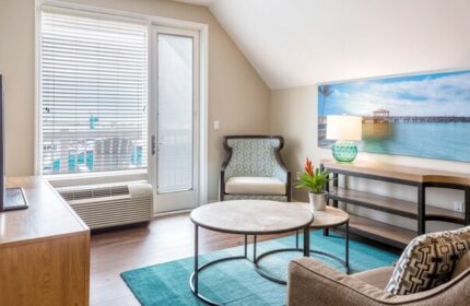 Opal Key Resort & Marina gay-friendly hotel room. Modern interior with ocean view art. Comfy chair, tables, and TV for a relaxing stay.