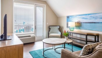 Opal Key Resort & Marina gay-friendly hotel room. Modern interior with ocean view art. Comfy chair, tables, and TV for a relaxing stay.