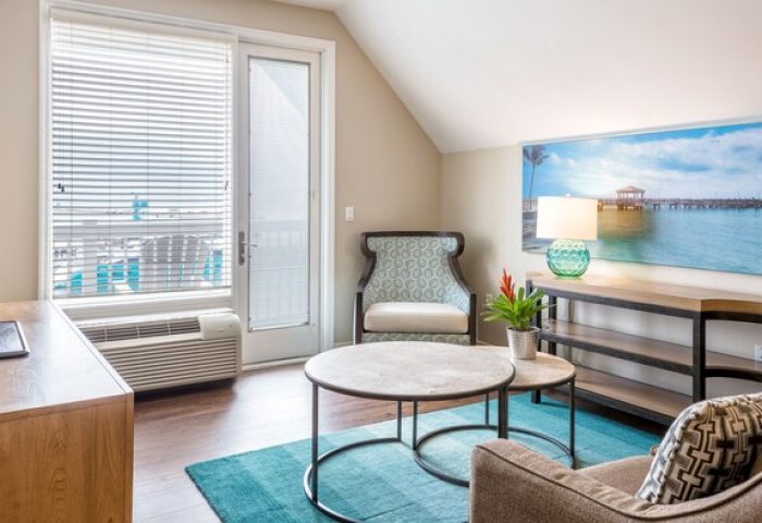 Opal Key Resort & Marina gay-friendly hotel room. Modern interior with ocean view art. Comfy chair, tables, and TV for a relaxing stay.