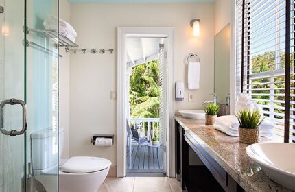 NYAH Key West gay-friendly hotel bathroom. Shower, toilet, and double sink vanity. Balcony view. Adults only travel.